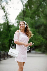 Portrait of young woman standing against trees