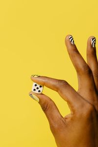 Close-up of woman hand against yellow background