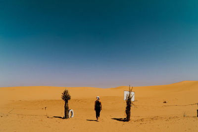 Rear view of woman walking on desert against sky