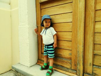 Portrait of happy boy standing against door