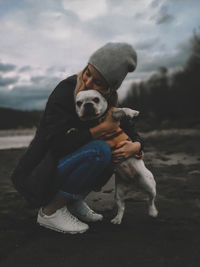 Woman embracing dog against sky