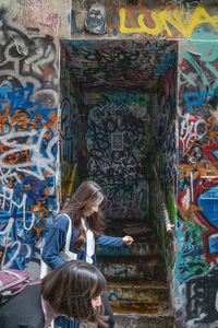 Rear view of two people against graffiti wall