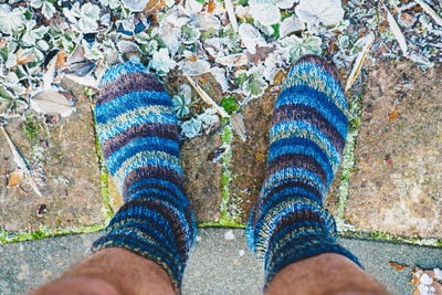 Low section of man in socks by frosted leaves on footpath
