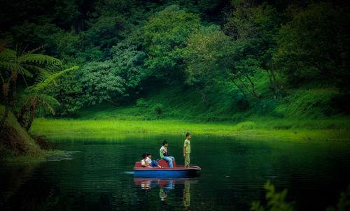 Rear view of people relaxing in lake