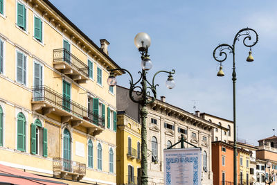 Low angle view of street lights by buildings against sky