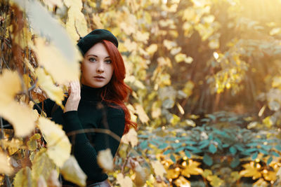 Portrait of young woman looking at tree