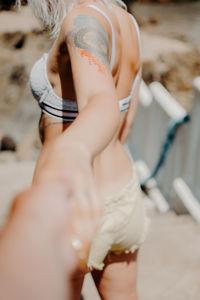 A couple on the beach walk hand in hand. perspective from the man's arm