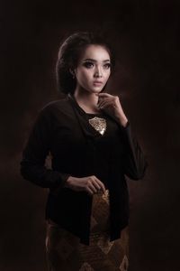 Fashionable young woman standing against black background