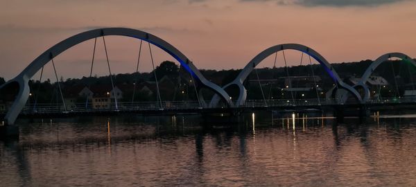 Bridge over river against sky during sunset