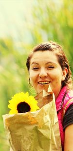 Portrait of woman holding sunflower in paper bag