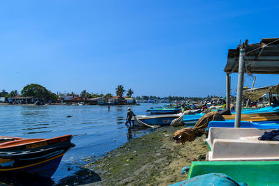 Fishing boats moored on sea against clear blue sky