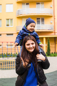 Portrait of smiling woman standing against building