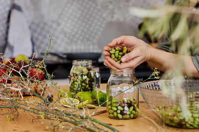 Woman prepares fermented olives in glass jars in the kitchen. autumn vegetables canning.