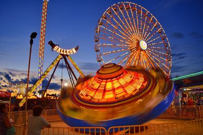 Low angle view of illuminated ferris wheel in amusement park at night