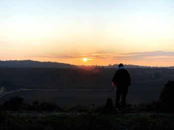 Rear view of silhouette man standing against sky during sunset