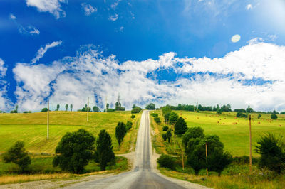 Road amidst field against sky