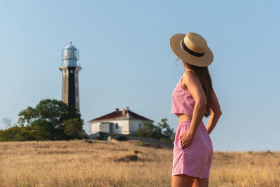 Rear view of woman standing on field against clear sky