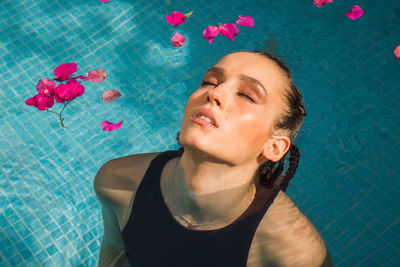Portrait of a beautiful young woman in swimming pool full of flowers 