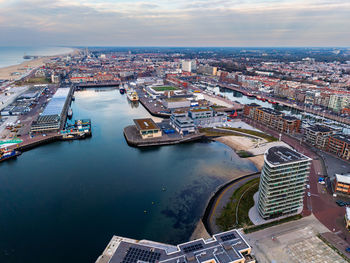 Aerial view of harbor city with curved docks, moored boats, and modern waterfront building framed