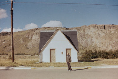 Woman standing on road against house