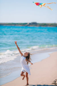 Smiling girl playing with kite on beach