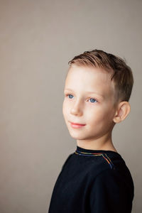 Portrait of boy looking away against gray background