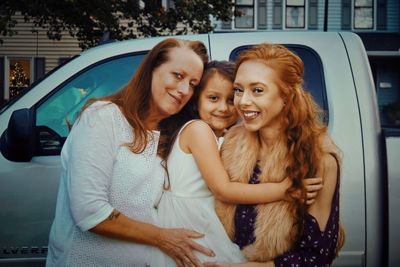 Portrait of smiling family against car