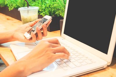 Midsection of person using mobile phone on table