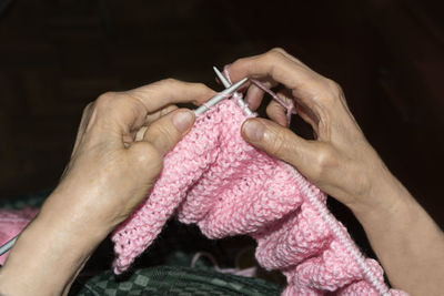 Midsection of senior woman knitting wool at home