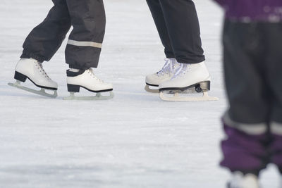 Low section of people ice-skating on ice rink during winter
