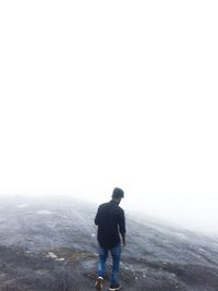 Rear view of man standing on landscape against clear sky