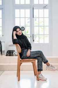 Young woman sitting on chair at home
