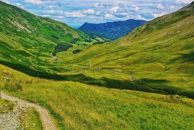 Scenic view of green landscape and mountains against sky