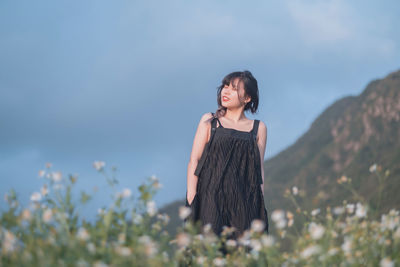 Young woman standing against sky