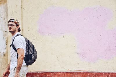 Portrait of man wearing sunglasses standing against wall