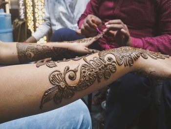 Midsection of woman getting henna tattoo