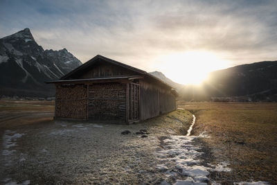 Scenic view of snow covered land and mountains against sky during sunset