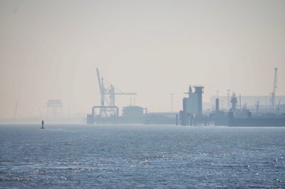 Cranes in city against clear sky