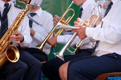Midsection of people playing trumpet at ceremony