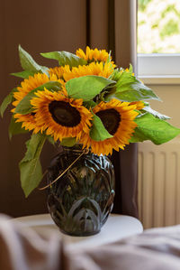 A bouquet of sunflowers in a vase by the window.