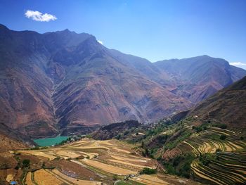 Scenic view of agricultural field by mountains against sky