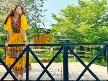 Portrait of young woman standing by railing