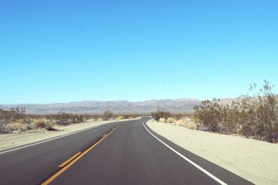 Road amidst landscape against clear blue sky