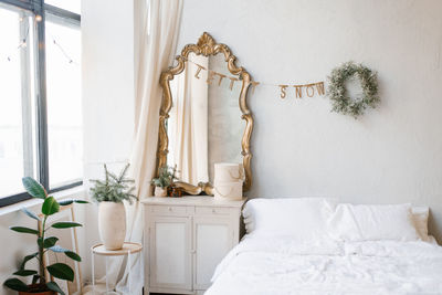 A double bed with white linens and pillows in the bedroom decorated for christmas and new year. 