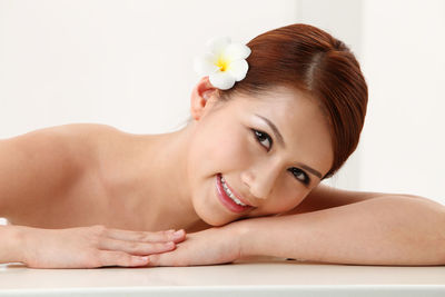 Portrait of smiling shirtless young woman wearing flower at home