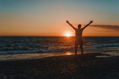 Woman standing on beach against sky during sunset