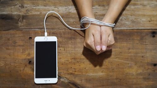 Low section of man using mobile phone on table