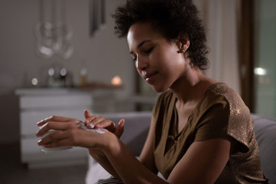 Glad mixed race woman applying cream on hands