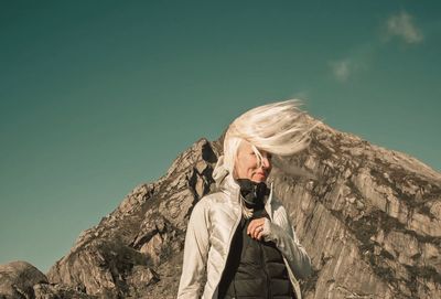 Portrait of woman standing on rock against sky