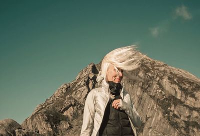 Mid adult woman standing against rock during sunny day